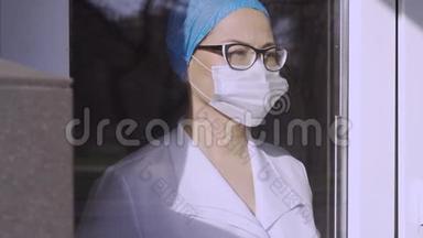 呼吸保健和生命安全，covid-19病毒。 女医生戴着外科口罩，穿着制服透过窗户